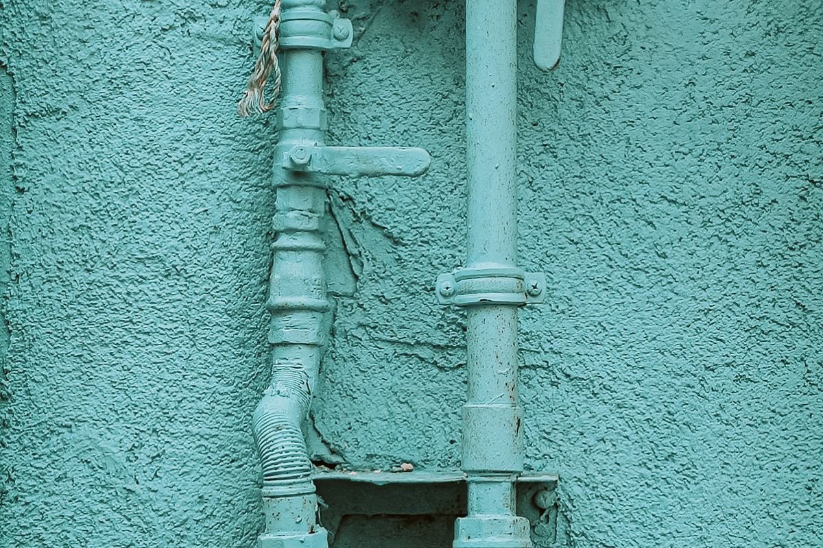 Blue gas meter with pipes on a building exterior wall