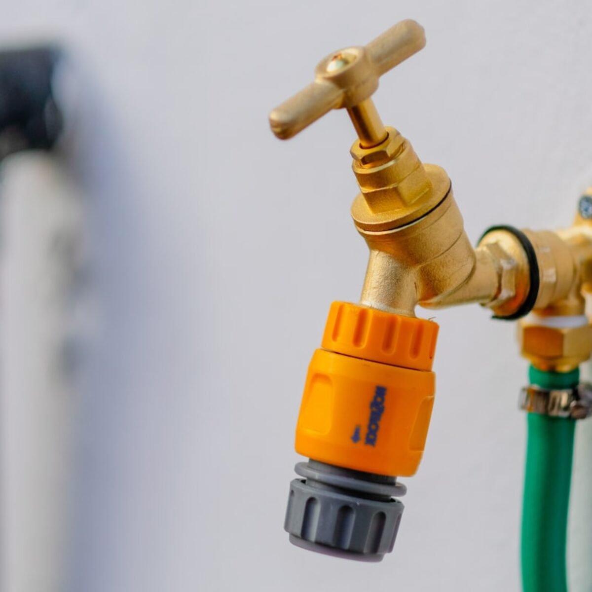 Brass outdoor garden tap mounted on an exterior wall, square crop