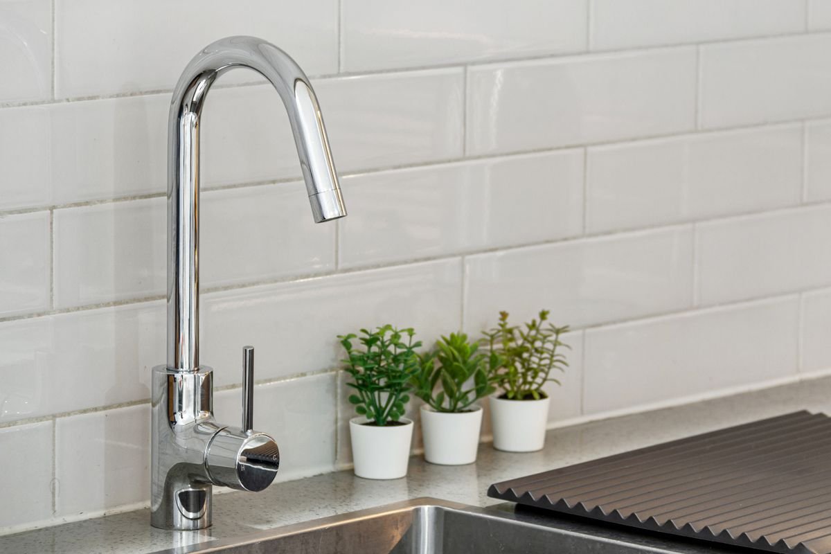 Kitchen sink with chrome tap and tiled splashback
