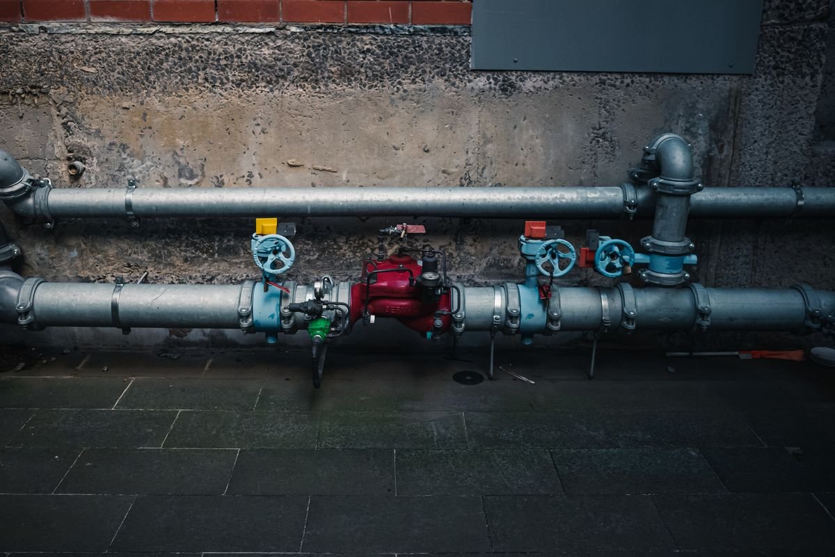 Pipes with coloured isolation valves on a wall