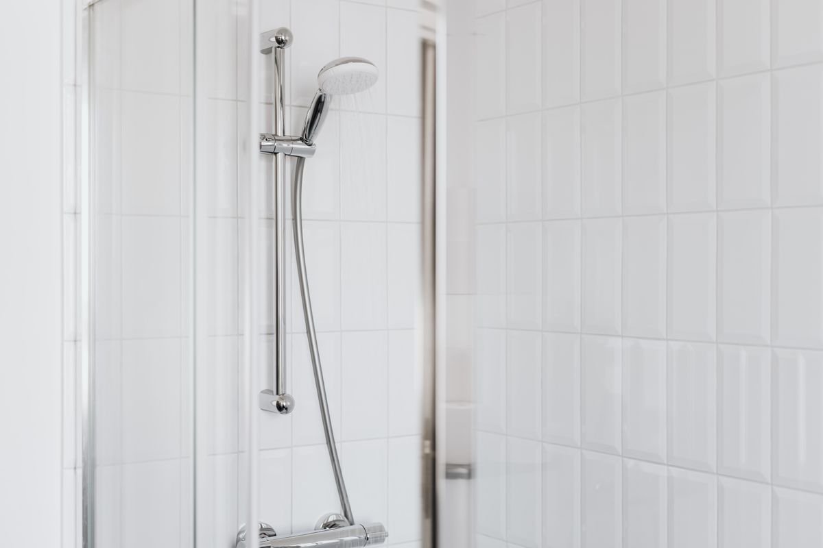 Shower with chrome fixtures and white tiles