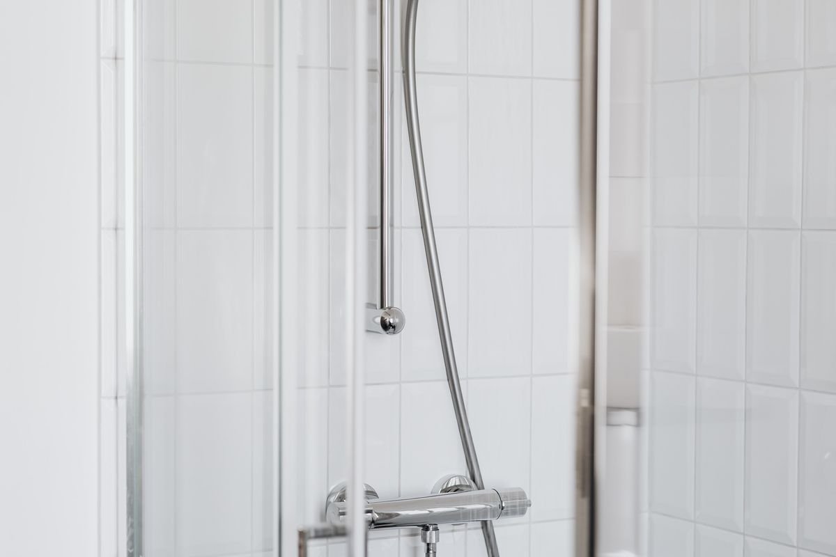 Stainless steel shower head on white tiles